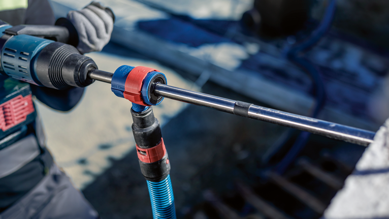 Una persona que usa equipo de seguridad utiliza una herramienta rotatoria para perforar hormigón.