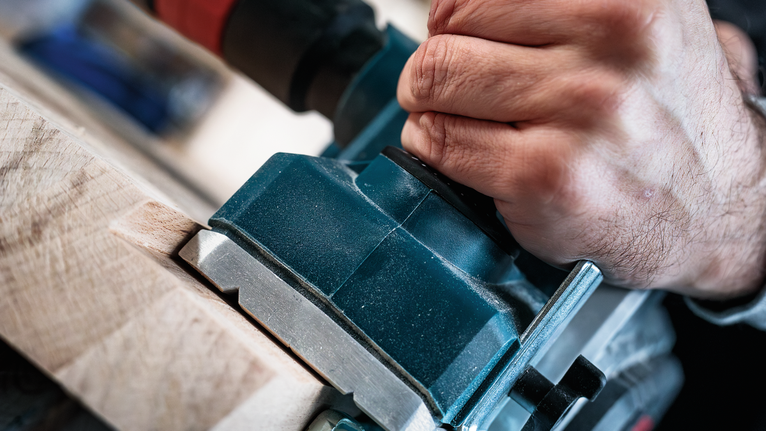 Persona utiliza una herramienta eléctrica para dar forma a la madera.