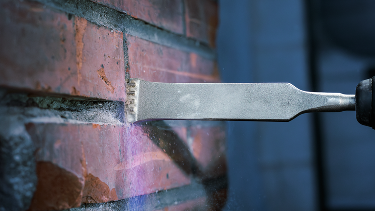 Herramienta de cincel para quitar mortero entre los ladrillos de una pared.