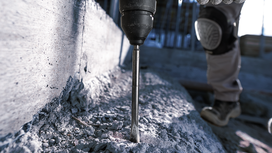 Una persona que usa equipo de seguridad perfora hormigón con un martillo perforador.