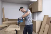 Una persona que lleva equipo de seguridad taladra un agujero en una tabla de madera en un taller.
