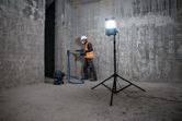Una persona que usa equipo de seguridad perfora una pared de concreto en un área de construcción.
