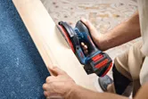 Una persona lija una tabla de madera utilizando una lijadora orbital aleatoria inalámbrica.