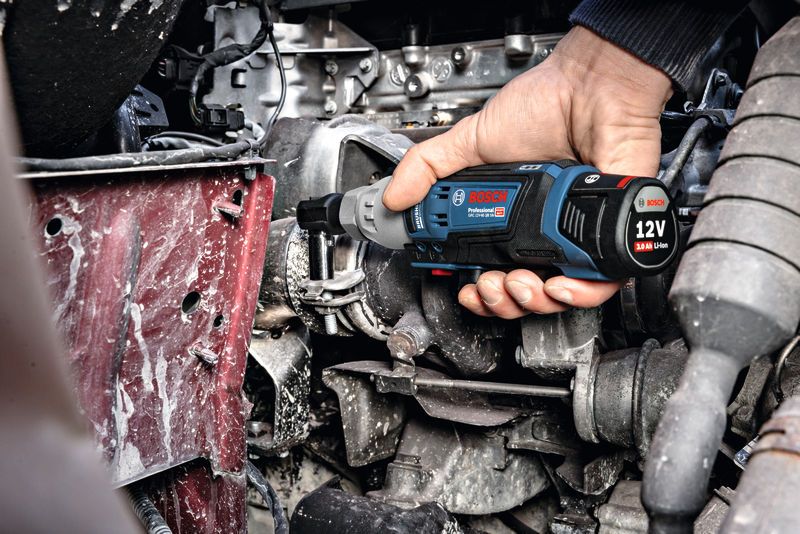 Una persona utiliza una llave de trinquete inalámbrica para apretar un perno en el compartimiento del motor.