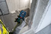 Una persona que lleva equipo de seguridad utiliza un medidor láser en una obra en construcción.
