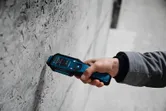 Una persona utiliza un medidor de humedad de materiales para comprobar los niveles de humedad en una pared de hormigón.
