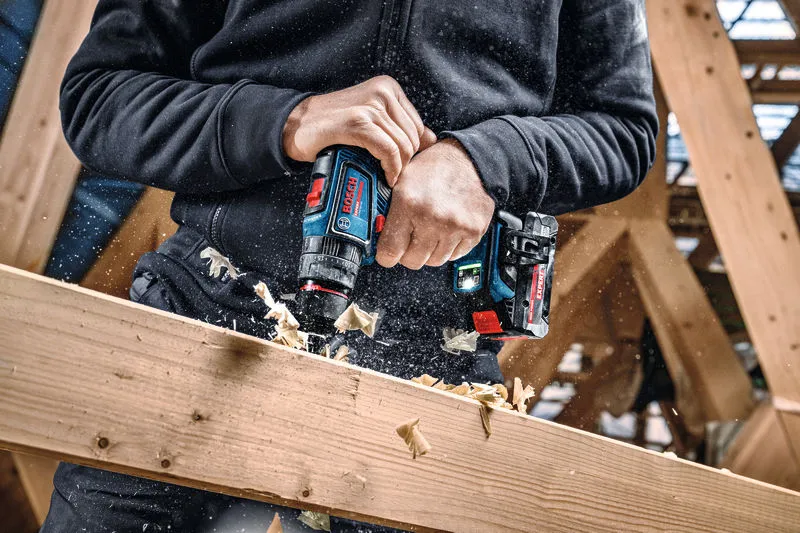 Una persona perfora una viga de madera utilizando una herramienta combinada inalámbrica.