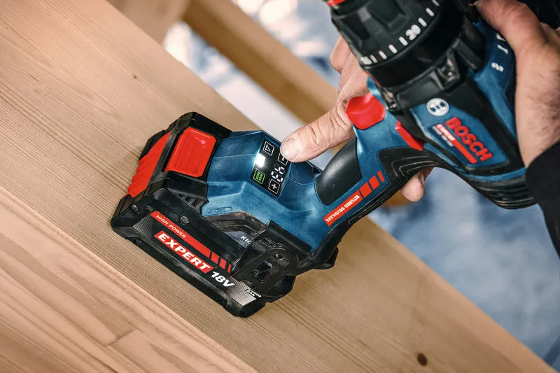 Una persona opera un taladro combinado inalámbrico sobre una viga de madera.