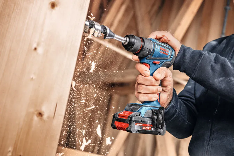 Una persona utiliza un taladro inalámbrico para hacer un agujero en una tabla de madera.