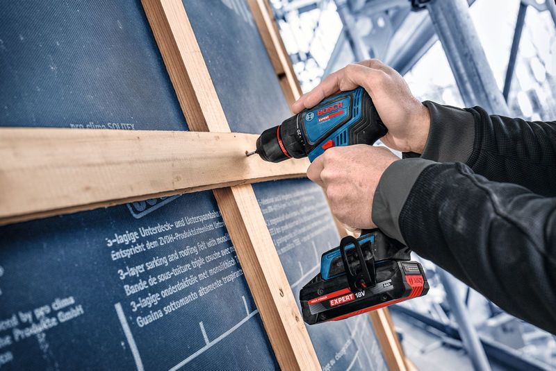 Una persona utiliza un taladro inalámbrico para fijar madera a un marco en el interior.