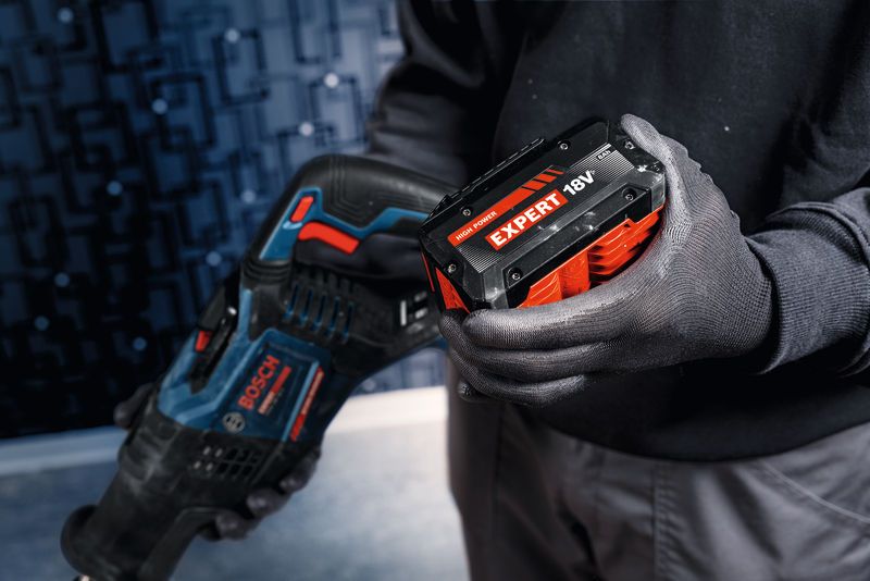 Una persona que usa equipo de seguridad sostiene una sierra alternativa inalámbrica con una batería de 18 V.