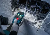 Una persona que usa equipo de seguridad usa un multicortador inalámbrico para cortar hormigón cerca de las barras de refuerzo.