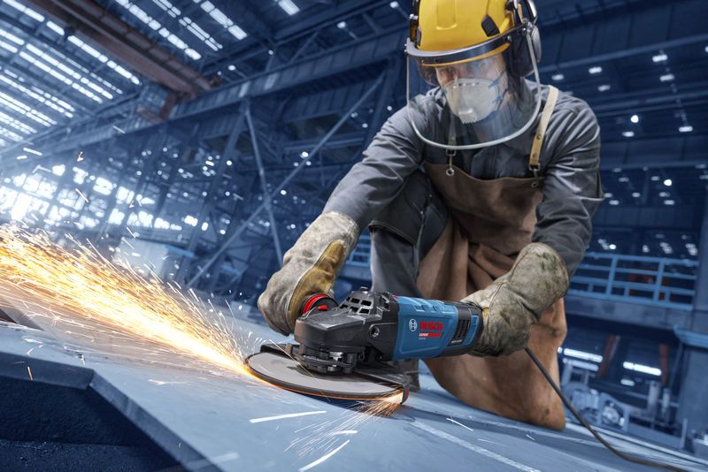 Una persona que usa equipo de seguridad muele metal, produciendo chispas brillantes.