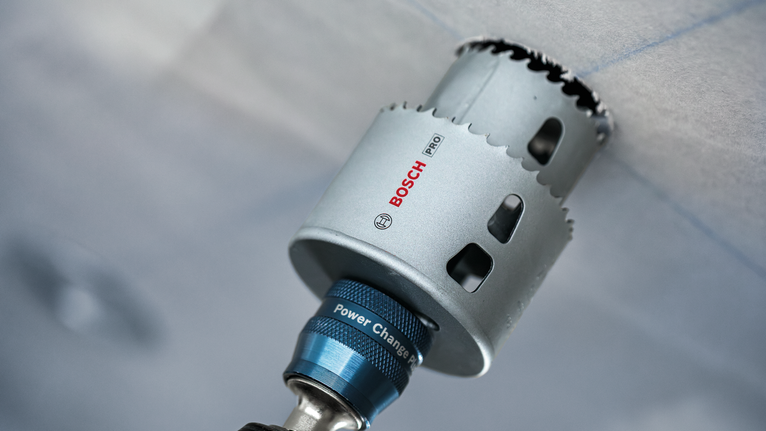 Accesorio de taladro con sierra de corona para cortar un panel de techo.