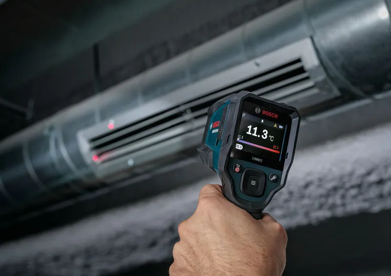 Persona utilizando un termómetro para medir la temperatura del aire en una rejilla de ventilación del sistema de climatización.