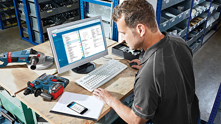 Un hombre trabaja en un escritorio con herramientas Bosch y una computadora.