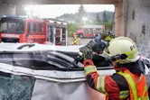 Turvavarusteita käyttävä henkilö leikkaa vaurioituneen ajoneuvon katon moottorisahalla.