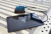 Tabletin lataus kannettavasta varavirtalähteestä USB-kaapelilla työpöydällä.