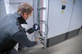 Turvavarusteita käyttävä henkilö tarkastaa sähköjohtoja tarkastuskameralla.