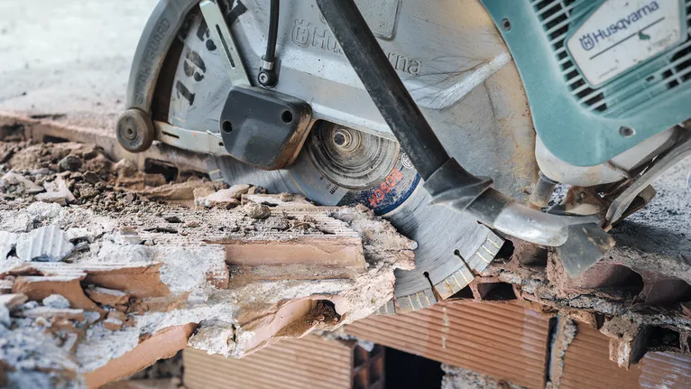 Leikkaussaha leikkaa karkeaa tiiliseinää.