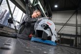 Turvavarusteita käyttävä henkilö valmistelee metallin katkaisusahaa metalliputken leikkaamista varten.