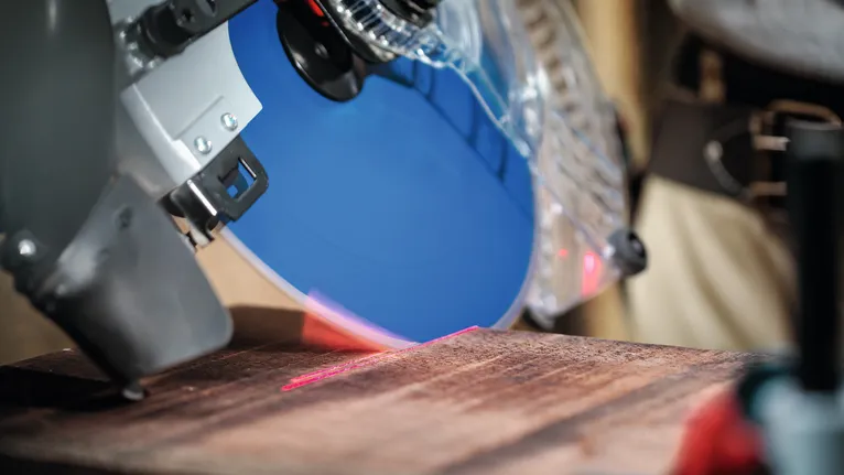 Laserohjaimella varustettu pyörösaha valmistautuu leikkaamaan puulevyä.