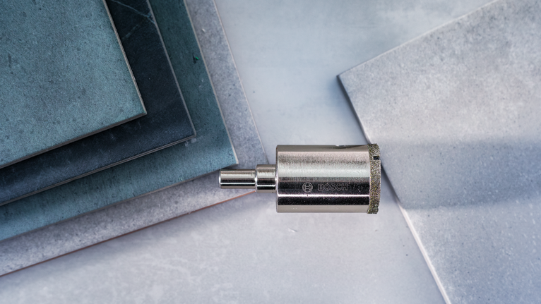 Timanttiporanterä asetettu pinottujen laattojen viereen vaalealle pinnalle.