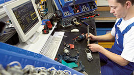 Mies työskentelee työpöydällä Bosch-työkalujen parissa tietokoneen edessä.