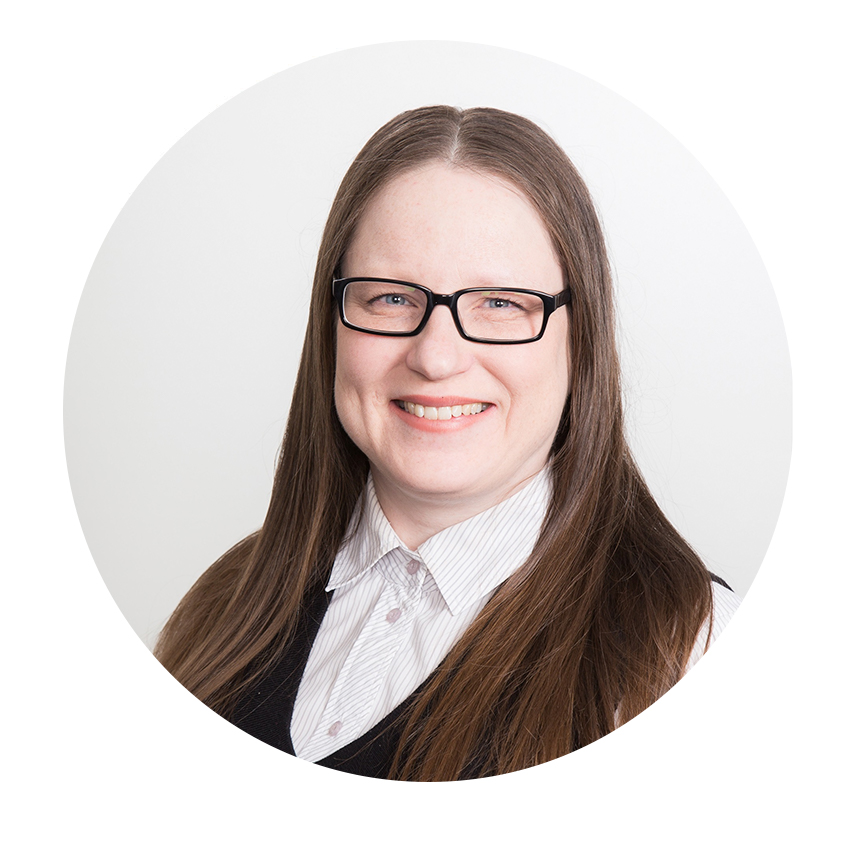 Nainen, pitkät hiukset, silmälasit, hymyilee vaaleassa ympäristössä.