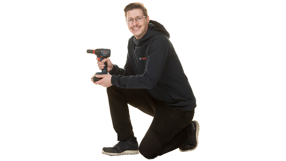 Nuori mies pitelee Bosch Professional -akkukäynnistintä polvillaan.