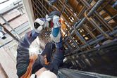 Une personne portant un équipement de sécurité broie des barres d'armature métalliques sur un chantier de construction.