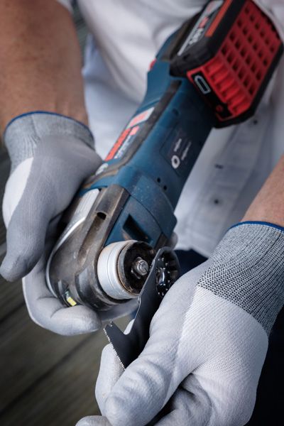 Une personne portant un équipement de sécurité fixe une lame de coupe à un outil électrique sans fil.