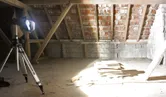 Une lampe de chantier sur un trépied éclaire brillamment les planches empilées dans un grenier inachevé.