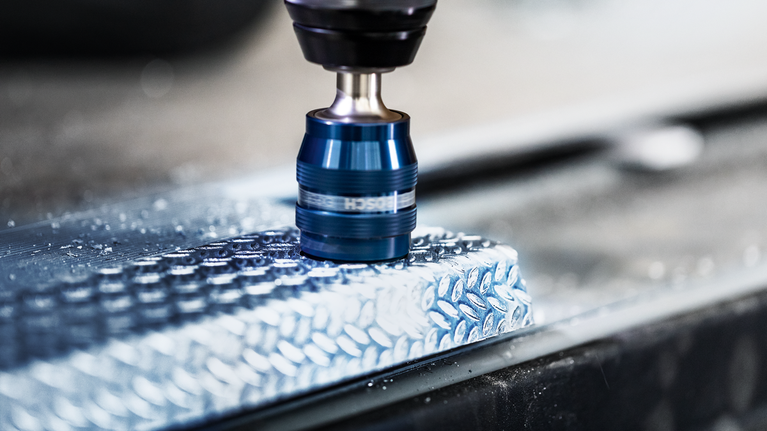 Un foret à métaux crée un trou dans une surface en aluminium texturée.