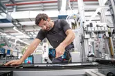 Une personne portant un équipement de sécurité utilise une perceuse sans fil sur une chaîne de montage industrielle.