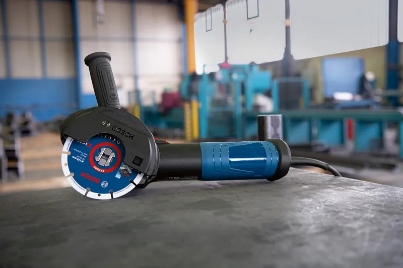 Meuleuse d'angle avec système X-LOCK posée sur un établi métallique dans un atelier.