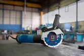 Meuleuse d'angle avec système X-LOCK posée sur un établi dans un atelier industriel.