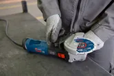 Une personne portant un équipement de sécurité fixe un disque de meulage sur une meuleuse d'angle.