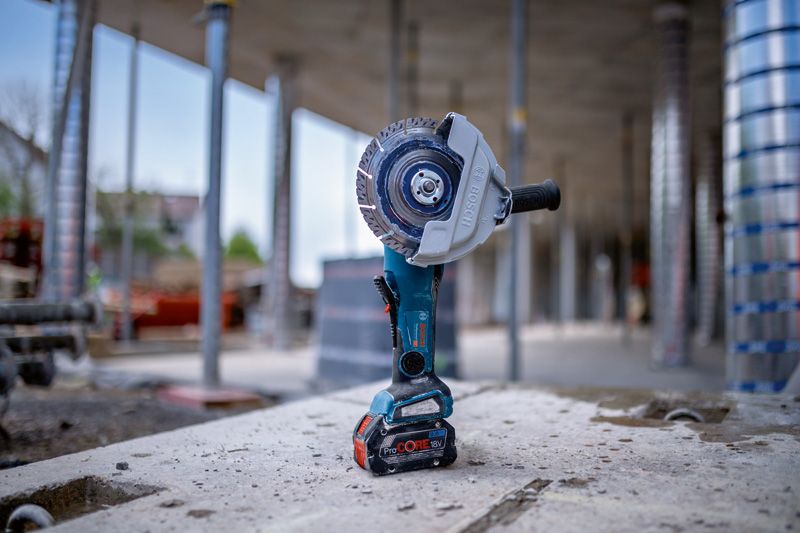 Meuleuse d'angle sans fil debout sur une surface en béton sur un chantier de construction.