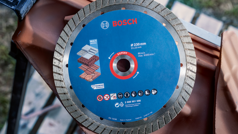 Disque à tronçonner diamanté affichant des icônes de compatibilité des matériaux sur un chantier de construction.