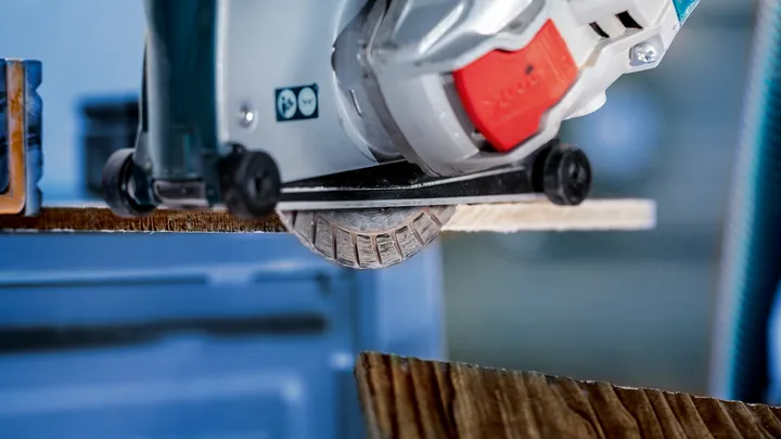 Scie circulaire coupant une planche de bois dans un atelier.