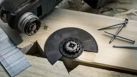 Accessoire de lame de scie circulaire pour la coupe du bois placé sur une planche de bois avec des clous à proximité.