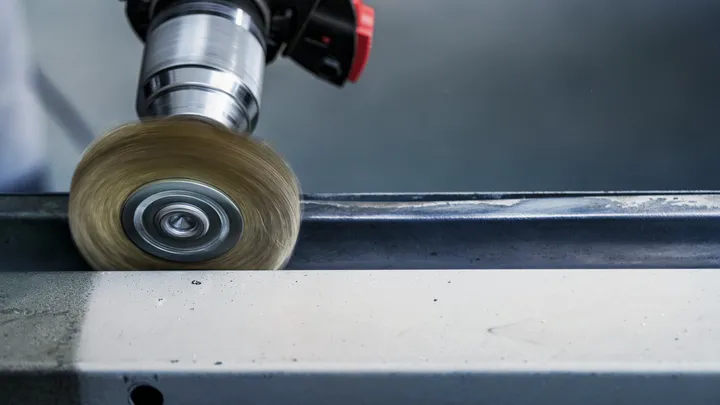 Meulage à la brosse métallique du bord d'une poutre métallique.