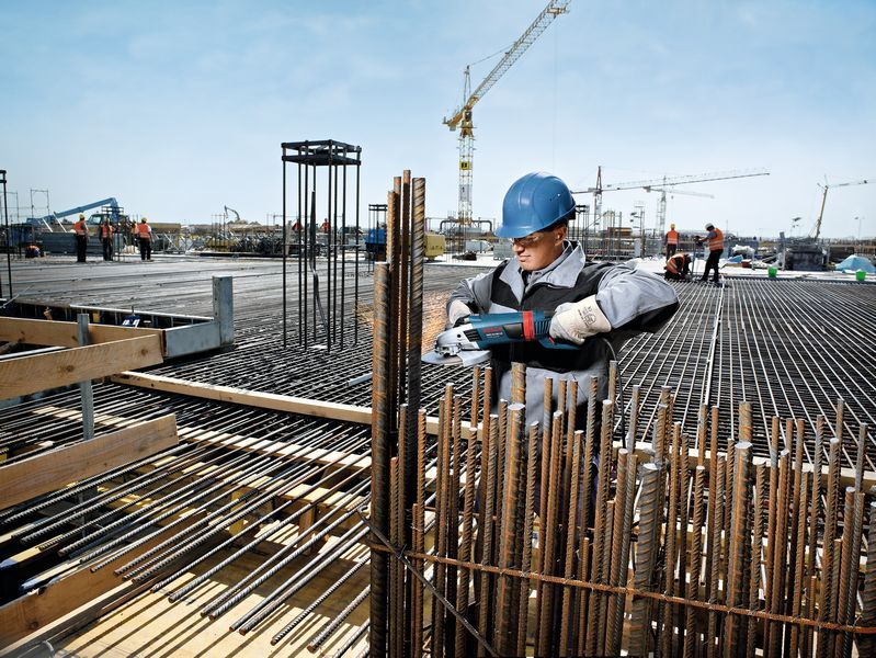 Ouvrier coupant des barres d'armature, chantier de construction.
