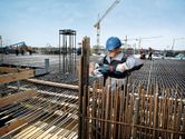 Ouvrier coupant des barres d'armature, chantier de construction.