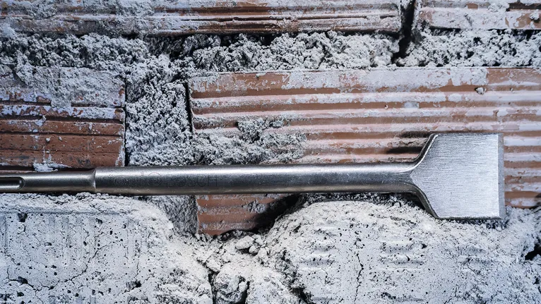 Foret à burin perçant un mur de briques et de mortier rugueux.