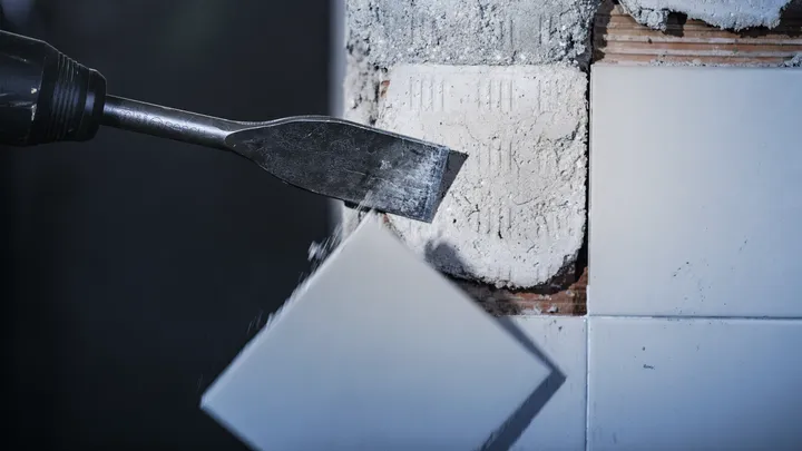 Outil de ciseau retirant un carreau mural du mortier.