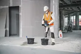 Une personne portant un équipement de sécurité utilise un mécanisme d’agitation pour mélanger le matériau dans un seau.