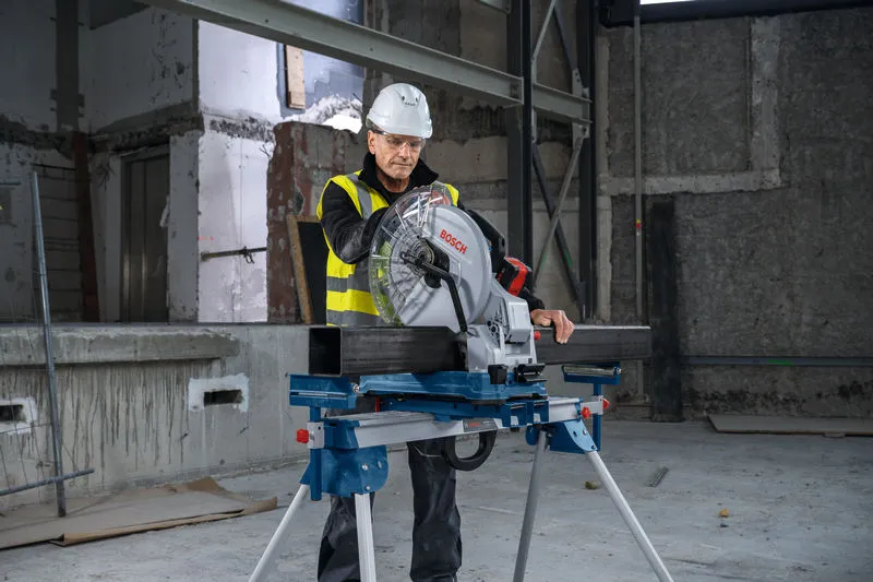 Une personne portant un équipement de sécurité utilise une scie à métaux sur un chantier de construction.