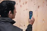 Une personne utilise un humidimètre pour matériaux afin de vérifier le taux d'humidité d'un mur en bois.